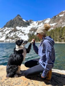 dog and owner by water and mountains