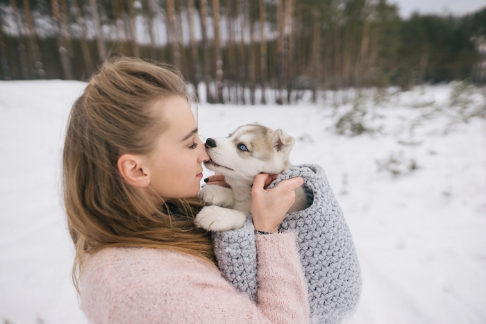 A woman holding a sick puppy showing cold-like symptoms like sore throat and watery eyes