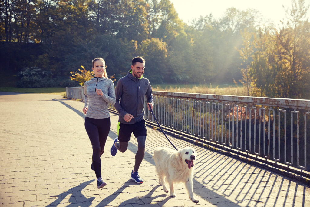 Happy couple with their dog running outdoors